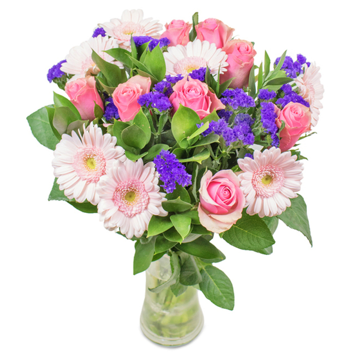 Set against a bright, clean backdrop typical of our Harold Hill studio, this hand-crafted arrangement boasts approximately eight mid-to-light pink roses, some just beginning to unfurl their classic swirls. Alongside them, five or six soft pink gerbera daisies-with their full, open faces and almost-white centres-bring balance and cheerful elegance to the composition. Vivid clusters of purple statice dot the bouquet, adding both colour contrast and intriguing texture, reminiscent of Harold Hill's wild borders in full bloom. Lush, robust green foliage establishes a foundation of freshness, while the clear vase allows the stems and sparkling water to become part of the visual symphony. Every detail of this beautifully curated bouquet speaks to occasions like birthdays, Mother's Day, or simply saying 'I care,' echoing the natural beauty and warmth of Harold Hill's neighbourhoods.